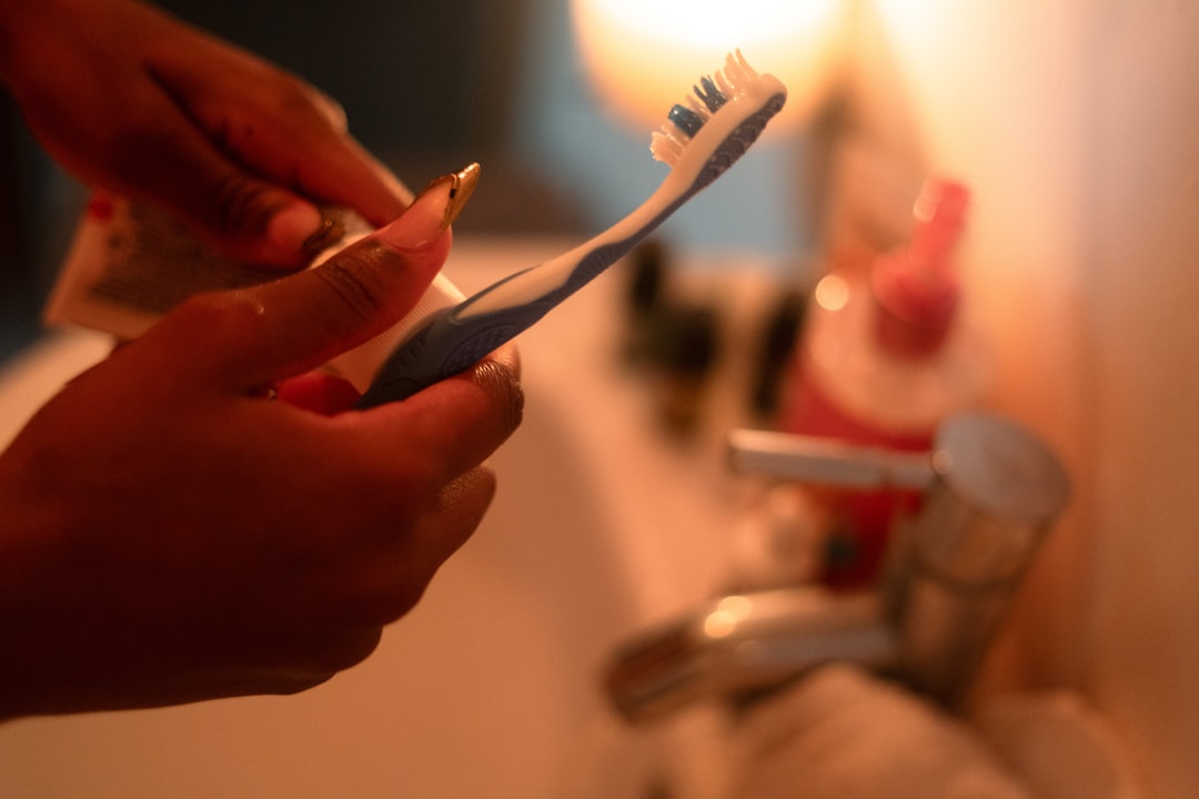 Hands squeezing toothpaste onto a toothbrush